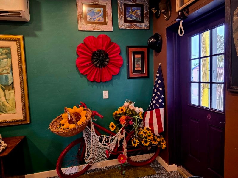 A repurposed bicycle decorated with a colorful display of flowers