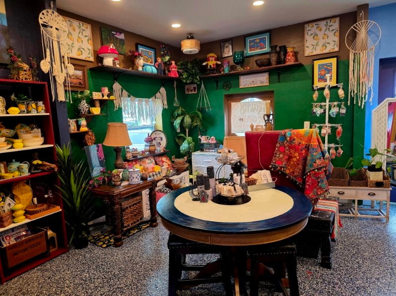 The shop's green room, filled with artwork, displays, and a round table